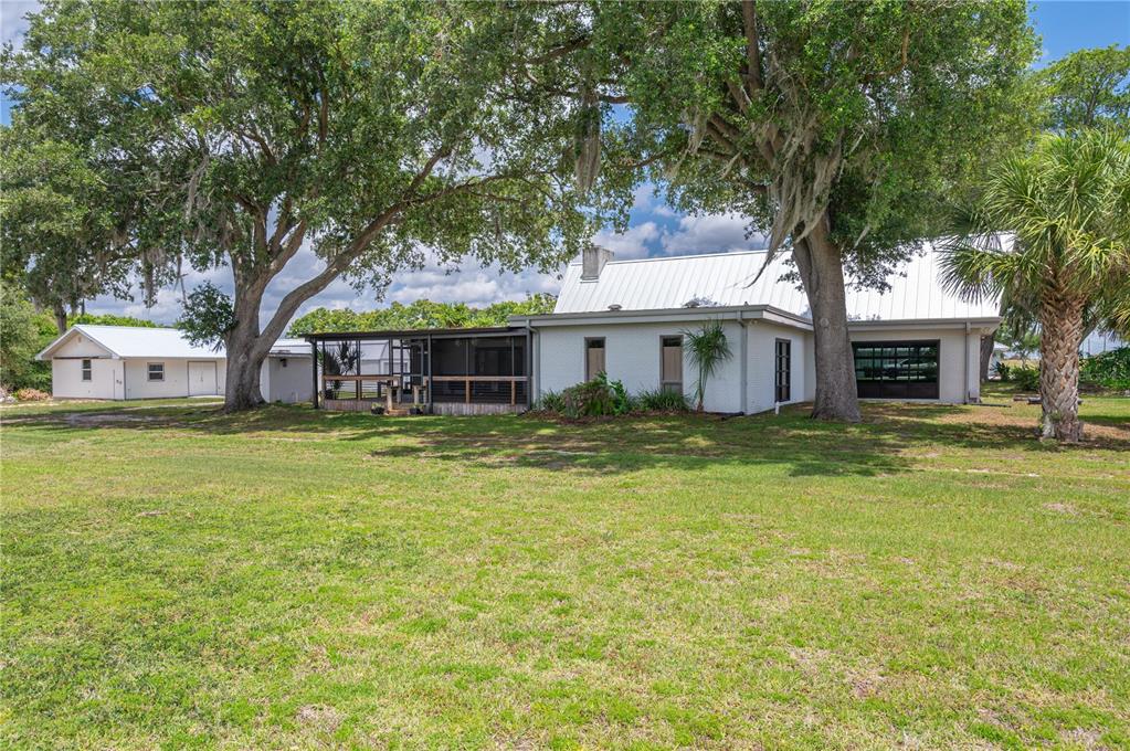 A white house with a metal roof and a screened porch sits on a lawn — 1325 THORNBURG ROAD, BABSON PARK, FL