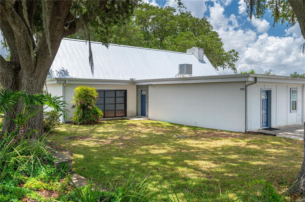 A white brick house with a metal roof and two blue doors sits on grass — 1325 THORNBURG ROAD, BABSON PARK, FL