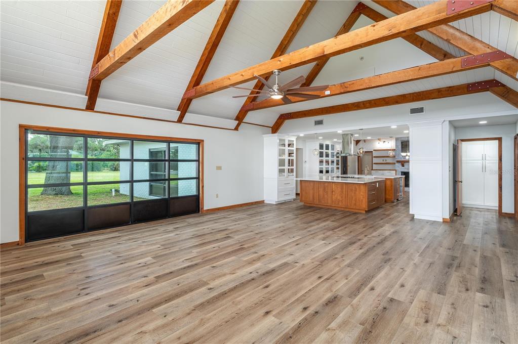 A spacious living area with vaulted wood-beamed ceilings, wood-look flooring, and an open kitchen — 1325 THORNBURG ROAD, BABSON PARK, FL