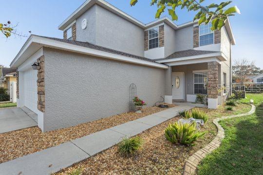 A two-story house with gray stucco siding, stone accents, and a concrete walkway — 5107 NE 122ND BOULEVARD, OXFORD, FL
