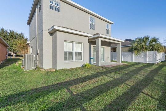 The exterior of a two-story beige house features a covered patio and a fenced backyard — 5107 NE 122ND BOULEVARD, OXFORD, FL
