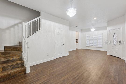 An interior view shows a staircase with wooden steps and a white railing in a room — 5107 NE 122ND BOULEVARD, OXFORD, FL