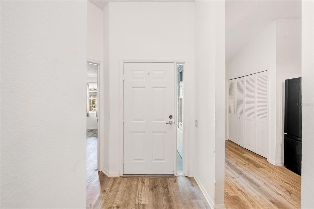 A white front door with a sidelight opens into a foyer with wood-look flooring — 39650 US HIGHWAY 19 N UNIT 712, TARPON SPRINGS, FL