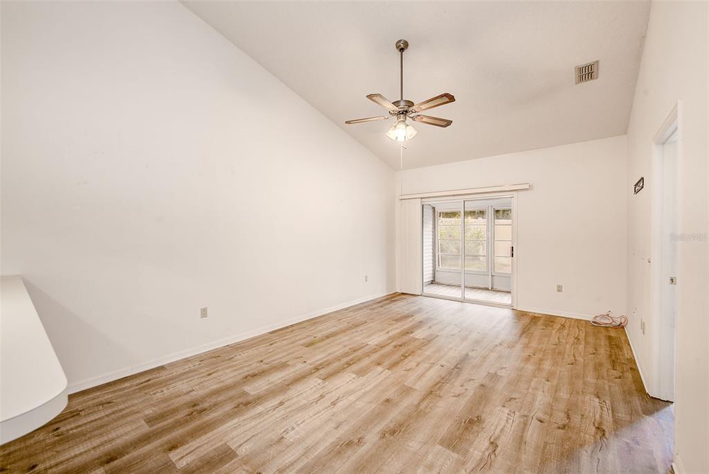 An empty room with wood-look flooring, a vaulted ceiling, a ceiling fan, and sliding glass doors — 39650 US HIGHWAY 19 N UNIT 712, TARPON SPRINGS, FL