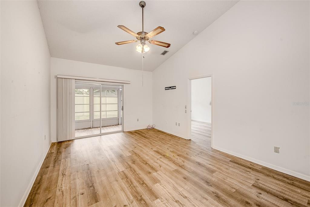 An empty room with wood-look flooring, a ceiling fan, and sliding glass doors to a patio — 39650 US HIGHWAY 19 N UNIT 712, TARPON SPRINGS, FL