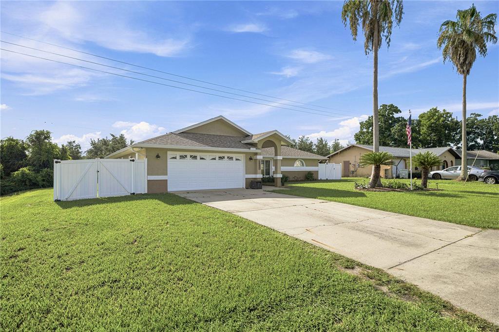 A single-story house with a white garage door, tan siding, and a concrete driveway — 2891 SW 140TH LOOP, OCALA, FL