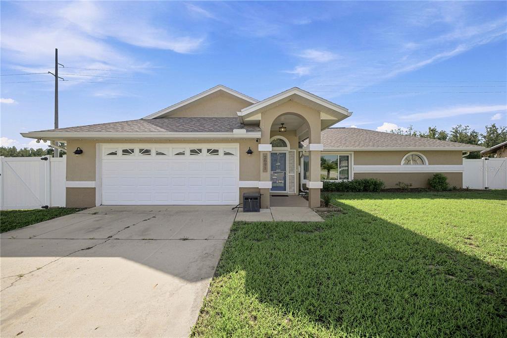 A bedroom features a bed with a wooden headboard, a ceiling fan, and a window — 2891 SW 140TH LOOP, OCALA, FL
