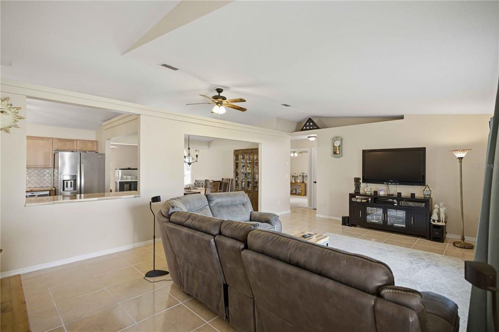 A tiled hallway leads past a living area toward an open kitchen with stainless appliances — 2891 SW 140TH LOOP, OCALA, FL