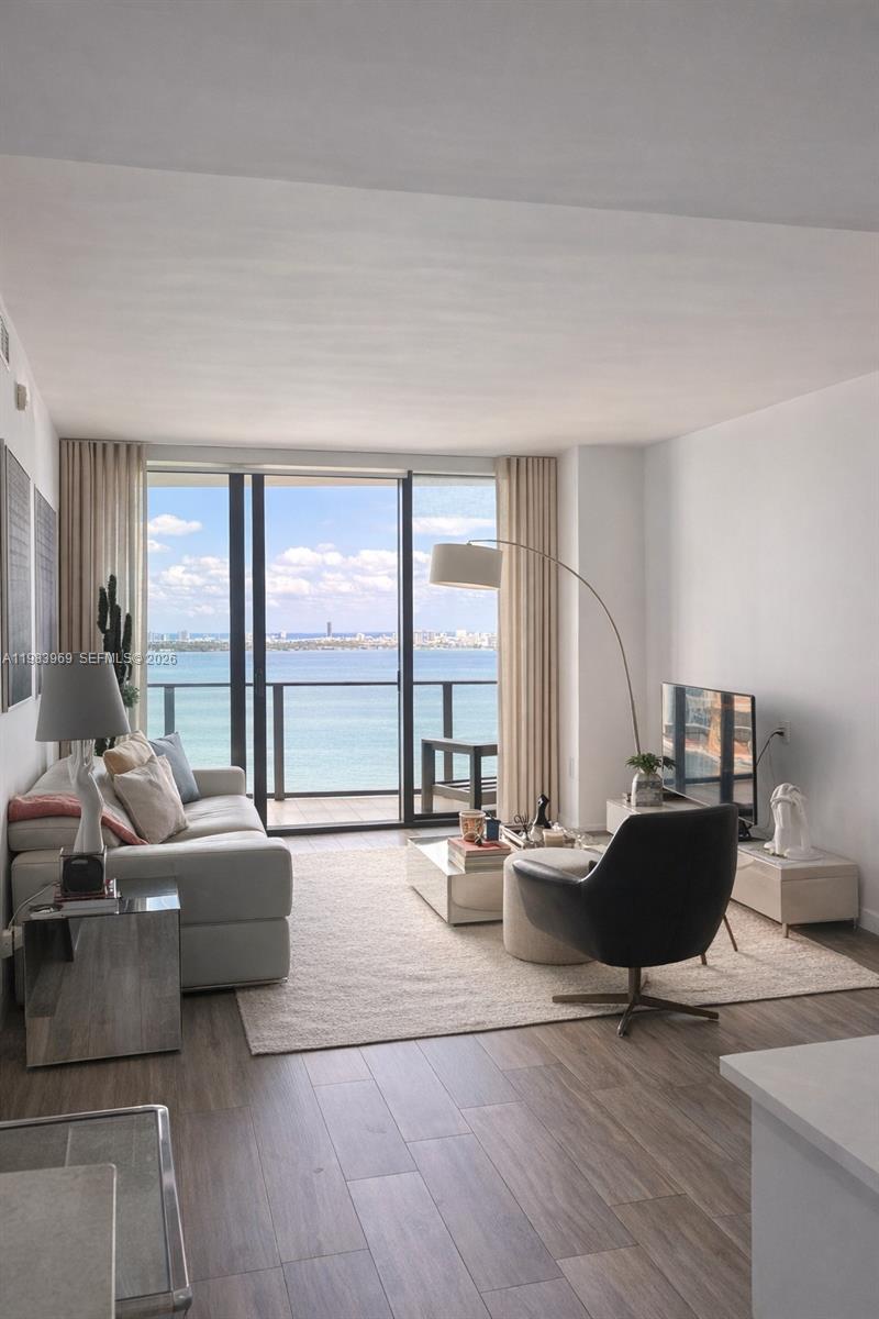A living room with a sofa, armchair, and floor-to-ceiling windows overlooking the ocean — 460 NE 28th St # 2807, Miami FL 33137, MIAMI, FL