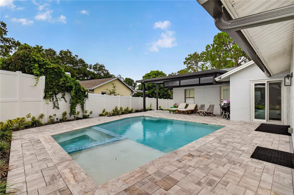 A backyard features a rectangular swimming pool with a tanning ledge and a paved patio area — 3775 SPRINGHILL CIRCLE, PALM HARBOR, FL