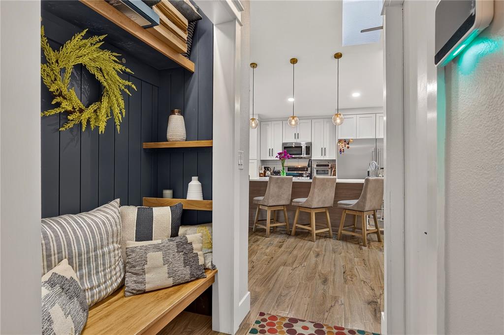 A view from a small entryway nook with a bench into a modern kitchen — 3775 SPRINGHILL CIRCLE, PALM HARBOR, FL