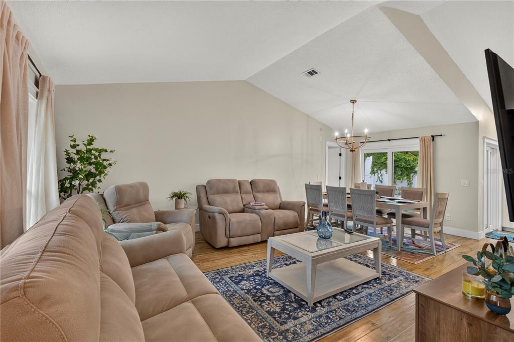 A living and dining area with vaulted ceilings, beige furniture, and a blue area rug — 3775 SPRINGHILL CIRCLE, PALM HARBOR, FL