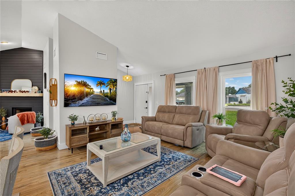 A living room features a mounted television, a wooden media console, and tan reclining furniture — 3775 SPRINGHILL CIRCLE, PALM HARBOR, FL