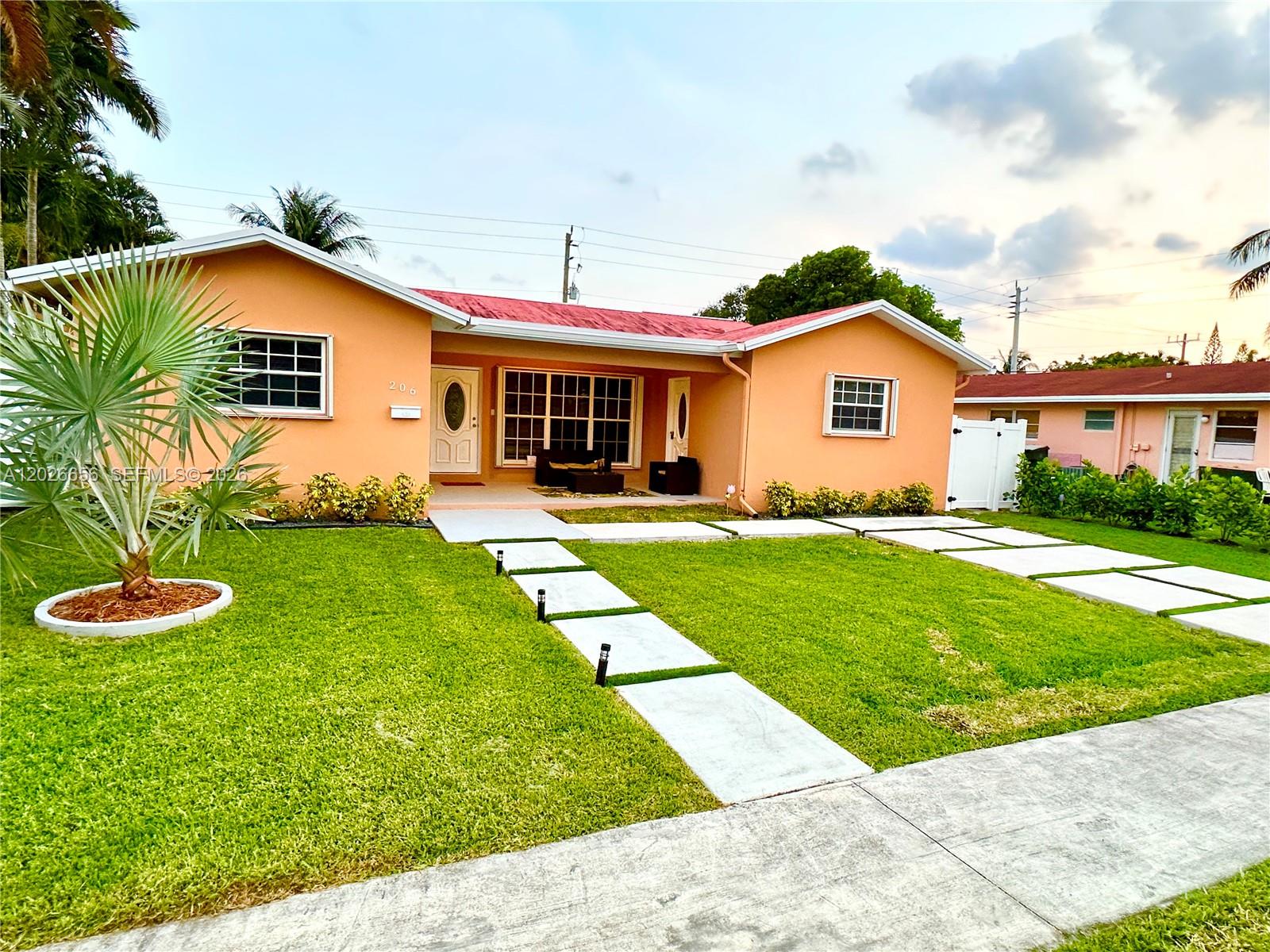 A peach-colored single-story house features a red roof, a front lawn, and concrete walkways — 206 SE 3rd Pl, Dania Beach FL 33004, DANIA BEACH, FL