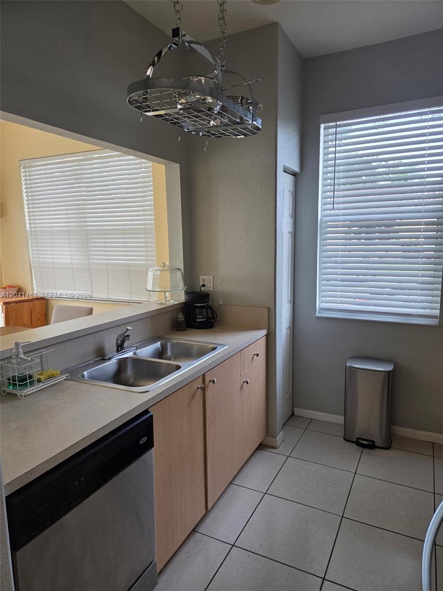 A kitchen features a double-basin sink, light wood cabinets, and a hanging metal pot rack — 23751 SW 110th Ave, Homestead FL 33032, HOMESTEAD, FL