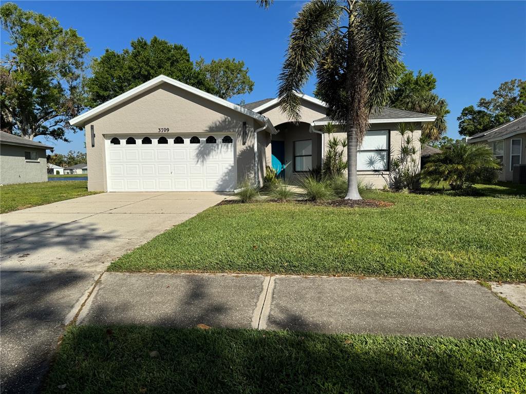 A single-story house with a beige exterior, a two-car garage, and a palm tree — 3709 62ND AVENUE E, BRADENTON, FL