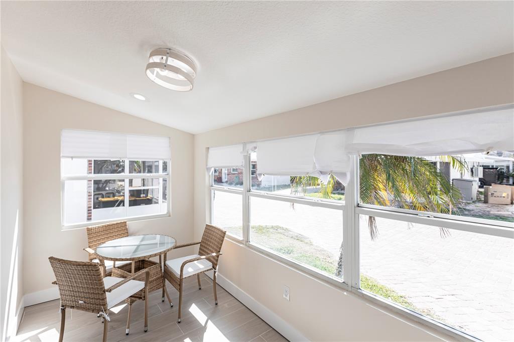 A sunroom features tile flooring, a small glass-topped table, wicker chairs, and large windows — 6020 MIDNIGHT PASS ROAD UNIT 15, SARASOTA, FL