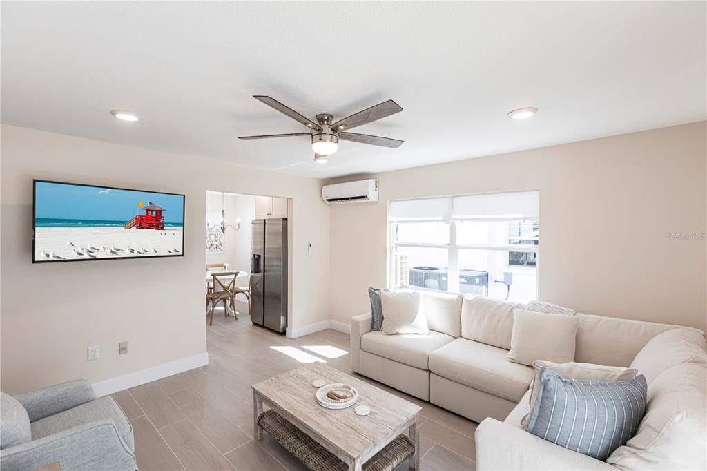 A living room features a white sectional sofa, a wooden coffee table, and a wall-mounted television — 6020 MIDNIGHT PASS ROAD UNIT 15, SARASOTA, FL