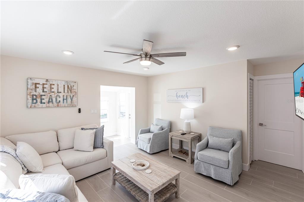 A living room features a white sectional sofa, two armchairs, and a wooden coffee table — 6020 MIDNIGHT PASS ROAD UNIT 15, SARASOTA, FL