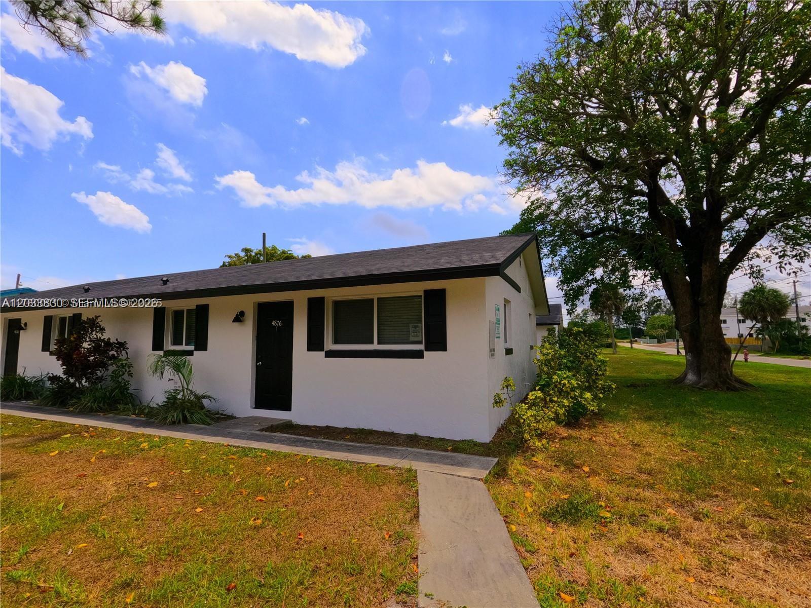 A single-story white house with black shutters and a black door sits on a lawn — 4938 Serafica Dr # 14, Lake Worth FL 33461, LAKE WORTH, FL