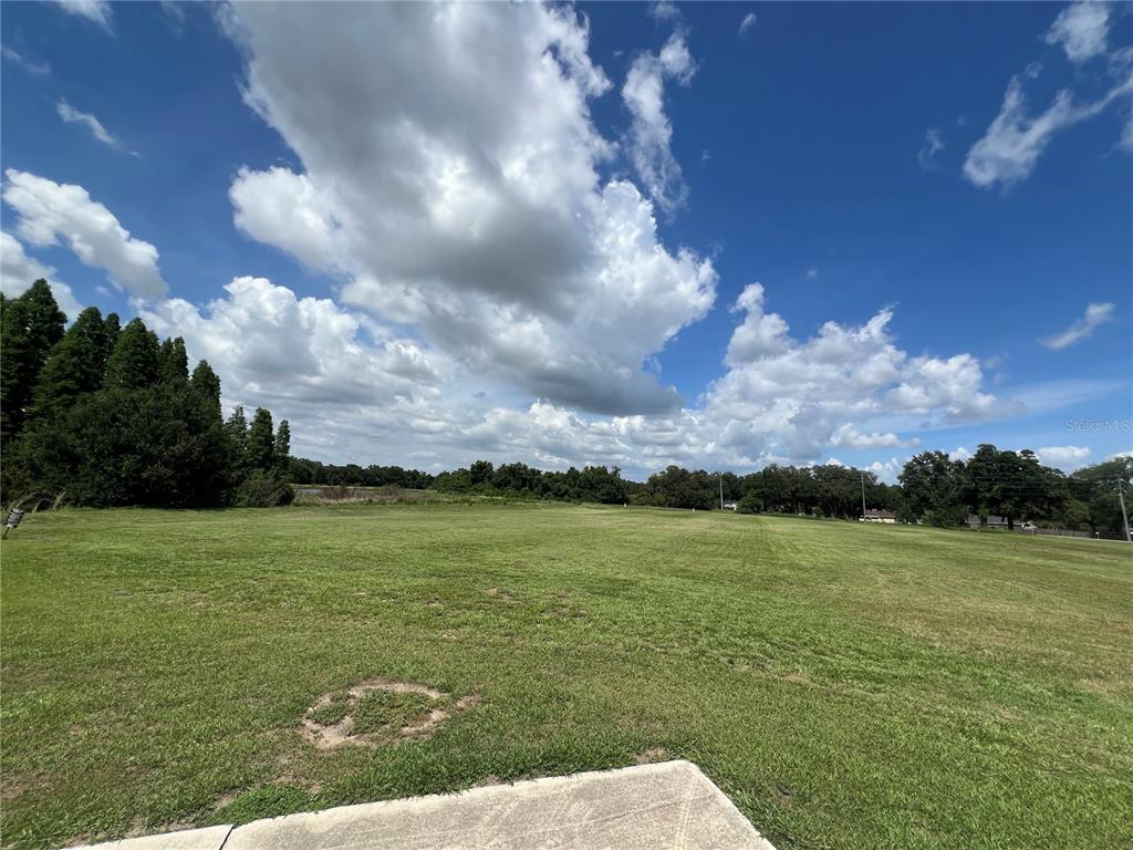 A large, grassy open field under a bright blue sky with scattered clouds — 4298 S PIPKIN ROAD, LAKELAND, FL