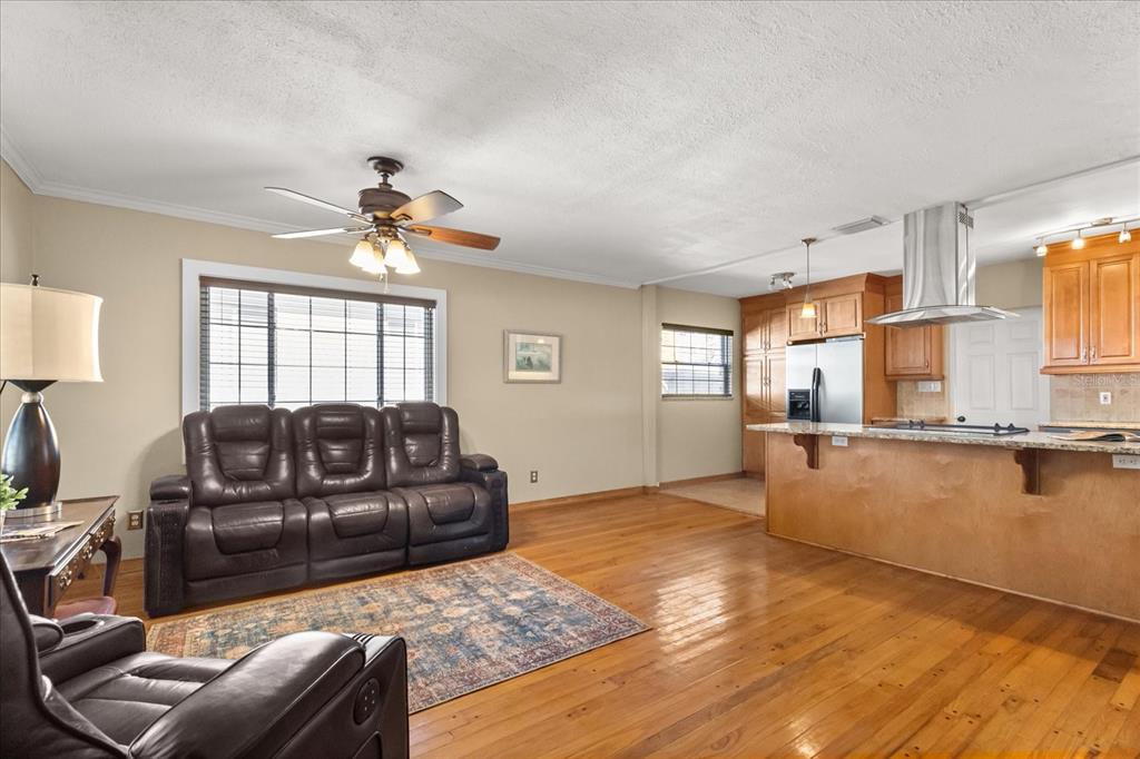 A living room with hardwood floors flows into an open kitchen with wooden cabinets — 4237 DR MARTIN LUTHER KING JR STREET N, ST PETERSBURG, FL