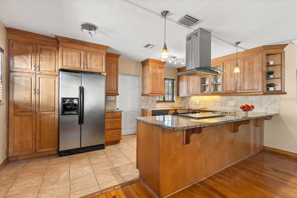 A kitchen features wood cabinets, stainless steel appliances, a granite island, and tile flooring — 4237 DR MARTIN LUTHER KING JR STREET N, ST PETERSBURG, FL