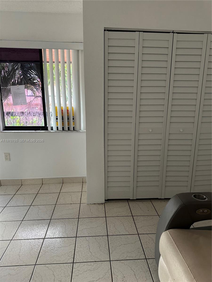 A room with white tiled floors, a window with vertical blinds, and white louvered closet doors — 2194 W 60th St # 22213, Hialeah FL 33016, HIALEAH, FL