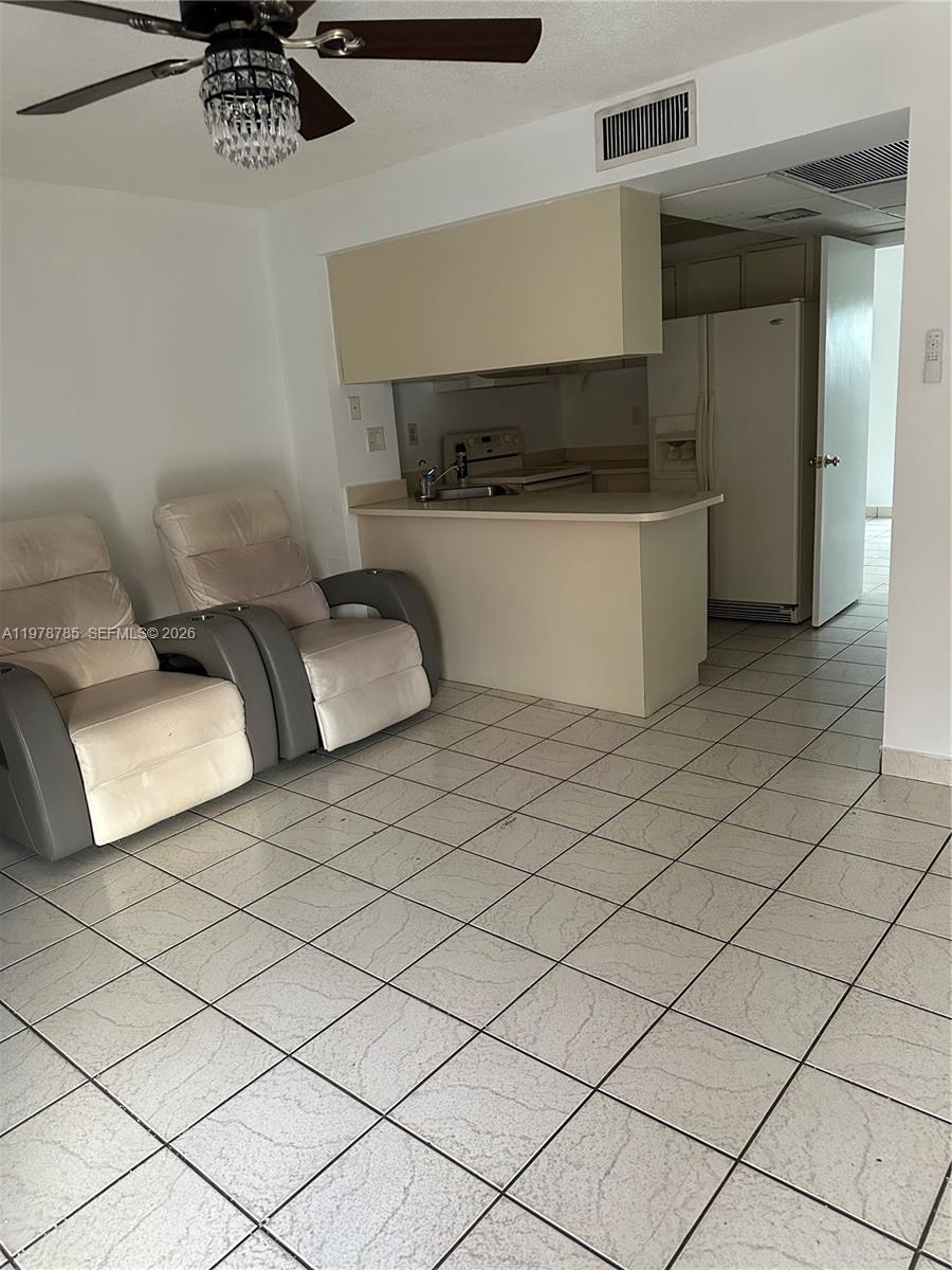 A kitchen with a breakfast bar and adjacent seating area features light-colored tile flooring — 2194 W 60th St # 22213, Hialeah FL 33016, HIALEAH, FL