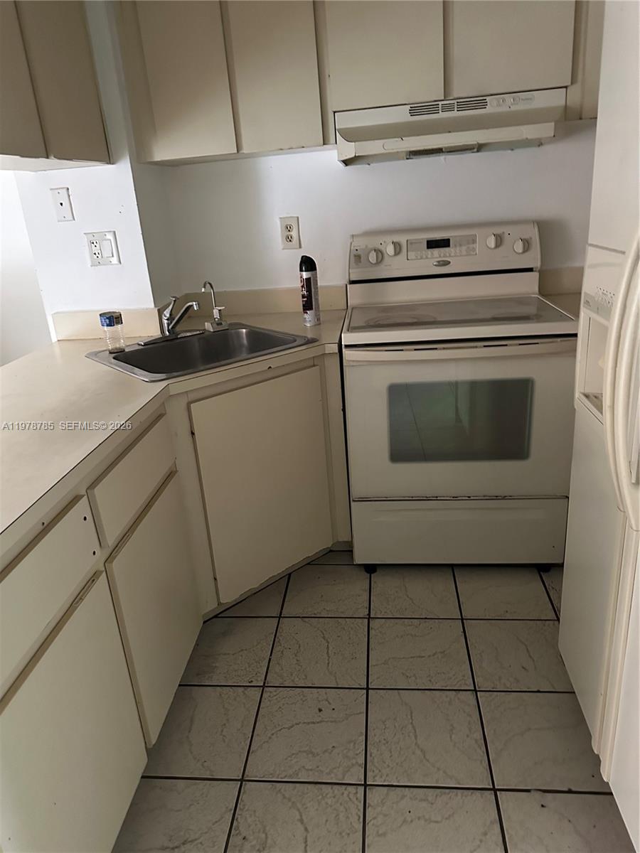 A small kitchen features white cabinets, a stainless steel sink, and a white electric range — 2194 W 60th St # 22213, Hialeah FL 33016, HIALEAH, FL