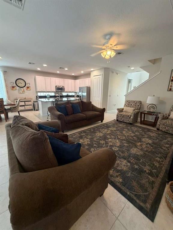 A living room with brown sofas, a patterned area rug, and an open kitchen — 4507 MONADO DRIVE, KISSIMMEE, FL