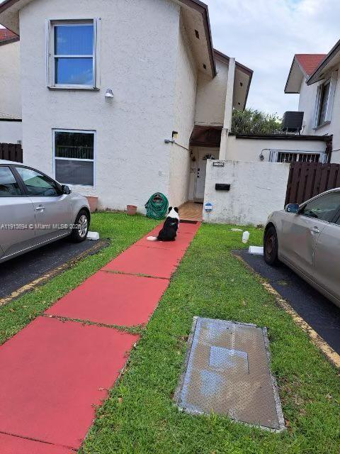 A dog sits on a red walkway between two parked cars in front of a house — 10454 NW 5th Ter # 30, Miami FL 33172, MIAMI, FL