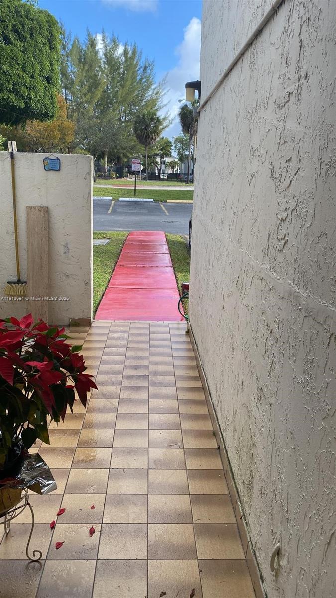 A tiled patio leads to a red-painted walkway outside a building with stucco walls — 10454 NW 5th Ter # 30, Miami FL 33172, MIAMI, FL