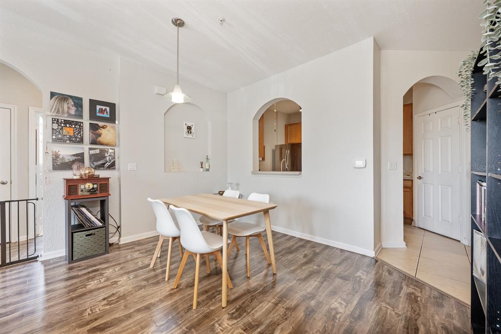 A dining area features a light wood table, four white chairs, and an arched cutout — 6335 CONTESSA DRIVE UNIT 301, ORLANDO, FL
