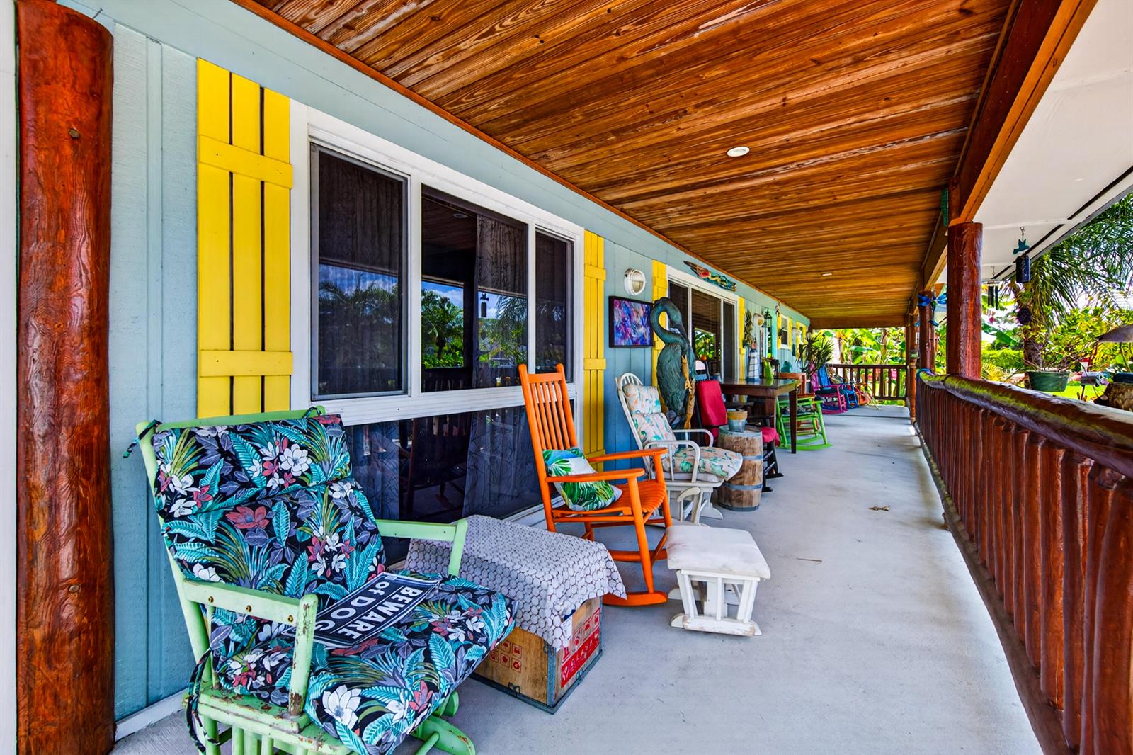 A covered porch features a wooden ceiling, light blue siding, yellow shutters, and several rocking chairs — 5135 Palm Ridge Boulevard, Delray Beach FL 33484, DELRAY BEACH, FL