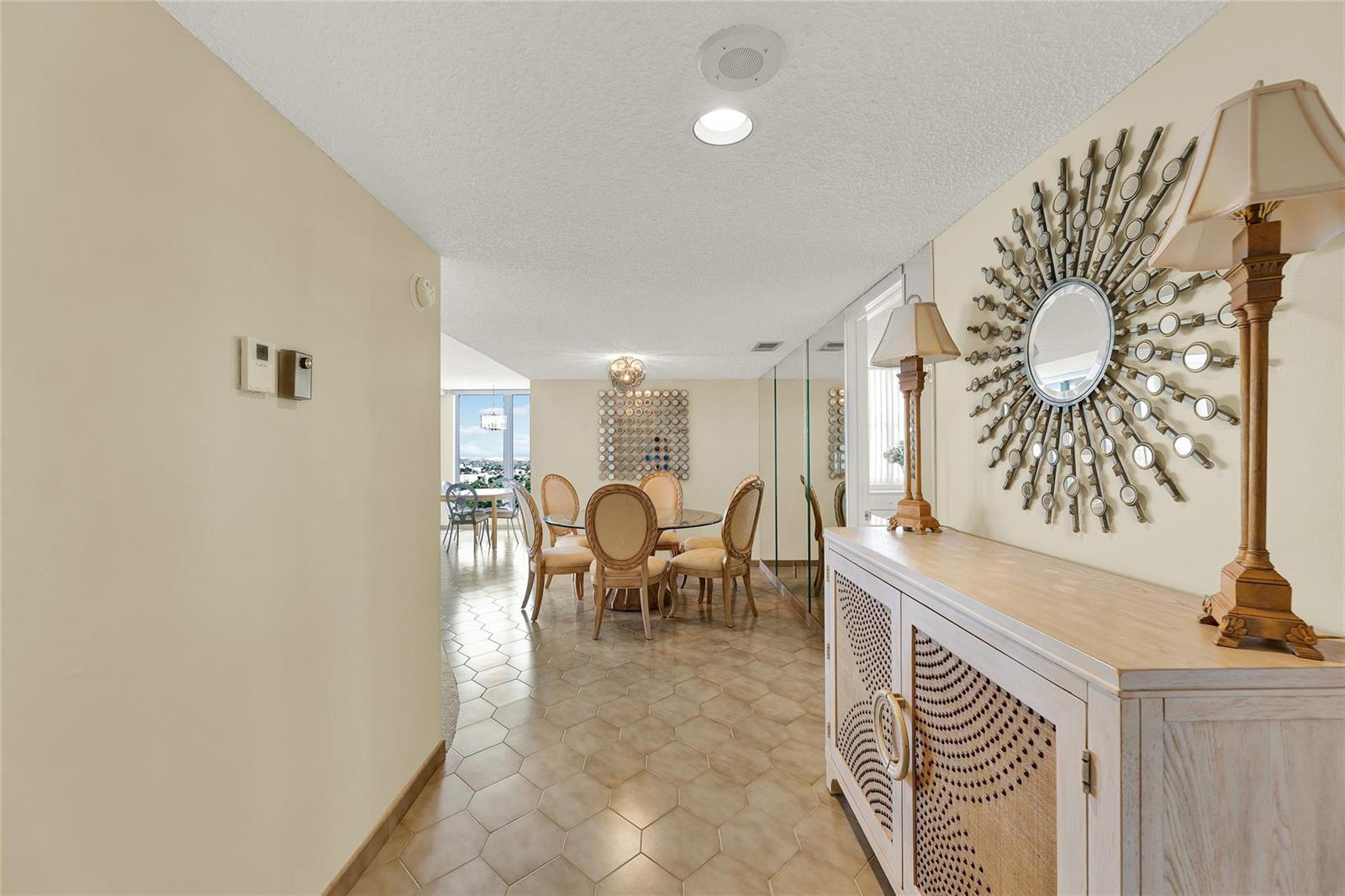A hallway with tile flooring leads to a dining area with a view of the city — 1010 S Ocean Boulevard # 1509, Pompano Beach FL 33062, POMPANO BEACH, FL