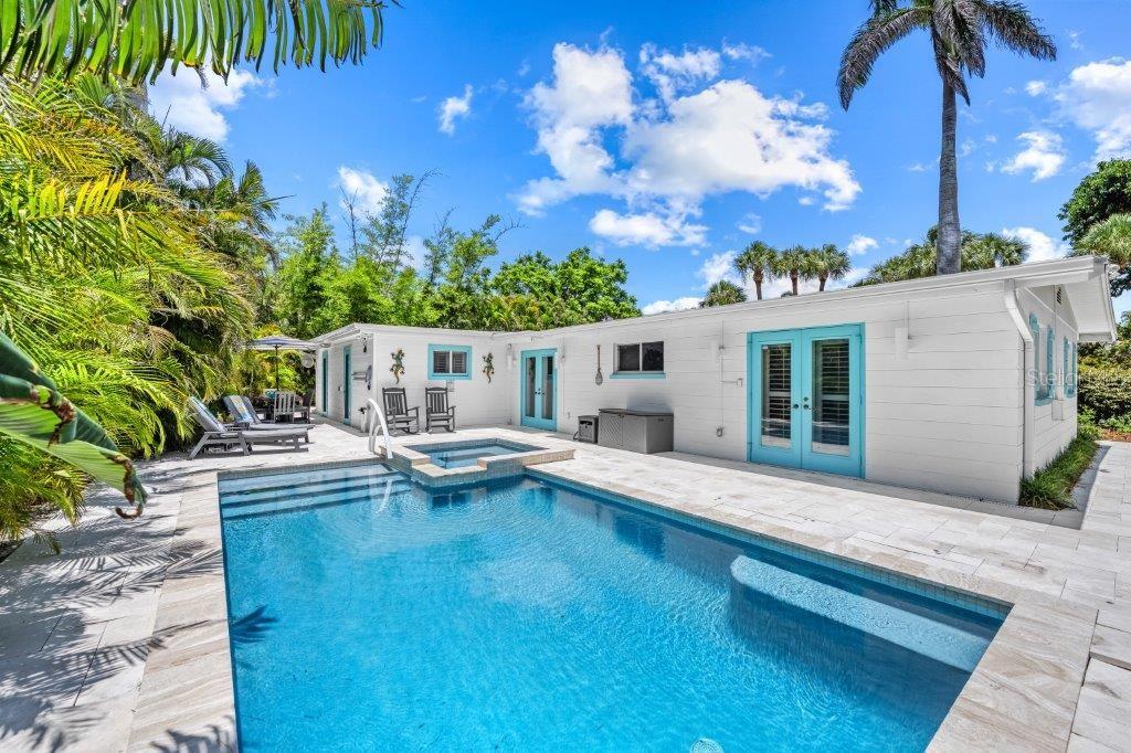 A backyard features a swimming pool with an attached spa and a white house exterior — 3360 HIGEL AVENUE, SARASOTA, FL