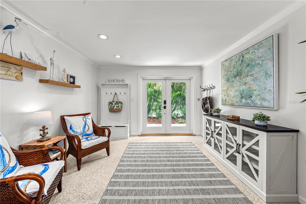 A bright entryway features a striped rug, wicker chairs, a storage cabinet, and double glass doors — 3360 HIGEL AVENUE, SARASOTA, FL