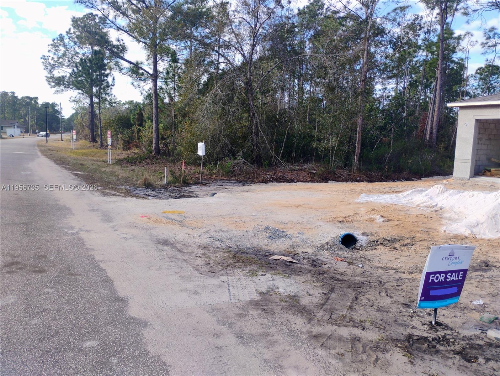 A dirt driveway leads to a construction site with a blue drainage pipe and sign — 4213 Gerona, Avon Park FL 33872, AVON PARK, FL