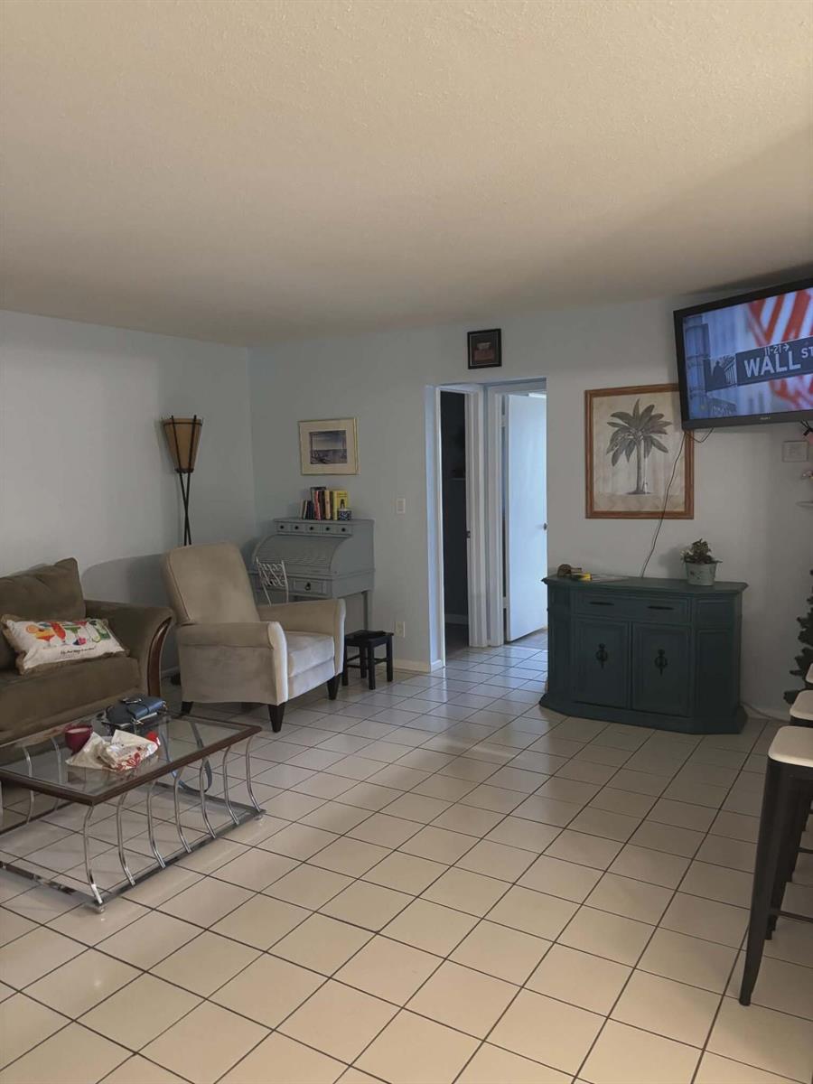A living room features light-colored tile flooring, a beige armchair, and a blue console table — 5550 N Ocean Boulevard # 106, Ocean Ridge FL 33435, OCEAN RIDGE, FL