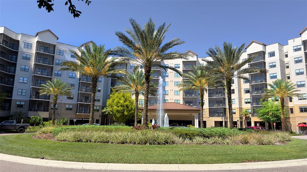 A multi-story apartment building features a circular driveway with a central fountain and palm trees — 14501 GROVE RESORT AVENUE UNIT 3211, WINTER GARDEN, FL