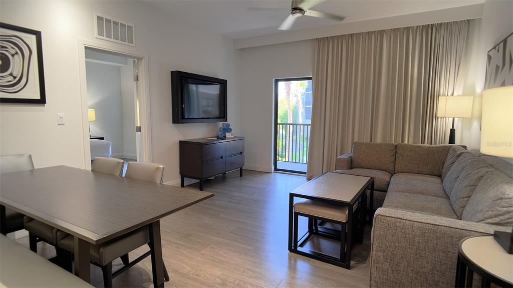 A living and dining area features wood-look flooring, a sectional sofa, and a balcony door — 14501 GROVE RESORT AVENUE UNIT 3211, WINTER GARDEN, FL