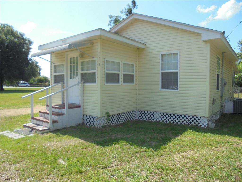 A yellow, single-story house with a small front porch, white trim, and lattice skirting — 1510 NE 55TH STREET, OCALA, FL