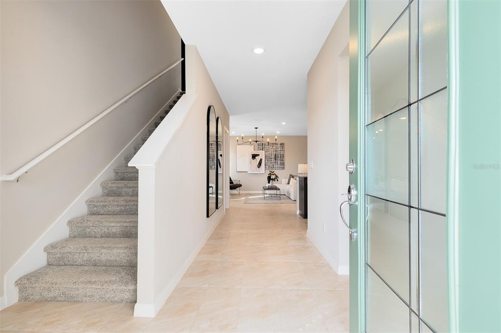 A bright entryway features a carpeted staircase, tiled flooring, and a view into the living area — 1186 FARM BRIDGE ROAD, ORLANDO, FL