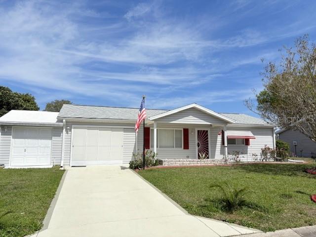 A single-story house with light siding, a white garage door, and an American flag — 9427 SE 174TH PLACE ROAD, SUMMERFIELD, FL