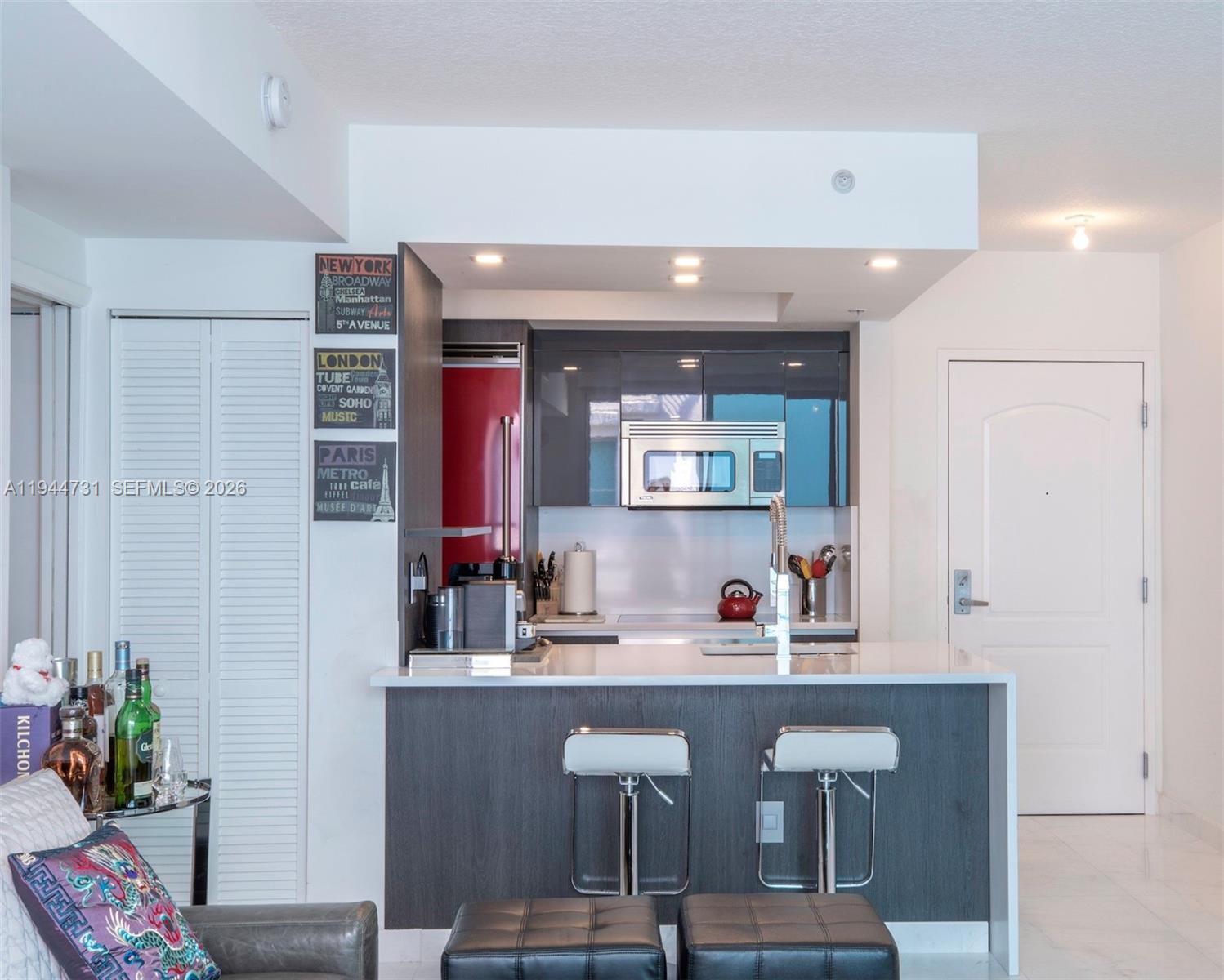 A kitchen features dark cabinetry, a white countertop, a breakfast bar with stools, and appliances — 110 Washington Ave # 1722, Miami Beach FL 33139, MIAMI BEACH, FL