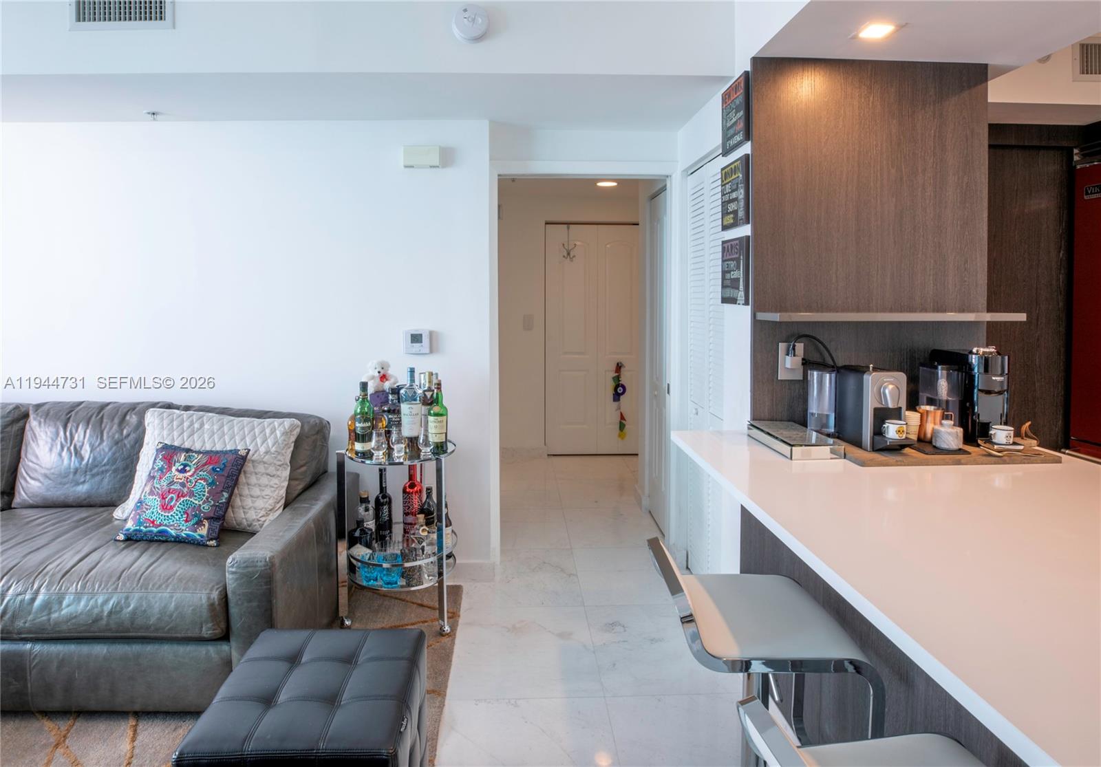 A living area with a leather sofa, bar cart, and kitchen counter with stools — 110 Washington Ave # 1722, Miami Beach FL 33139, MIAMI BEACH, FL