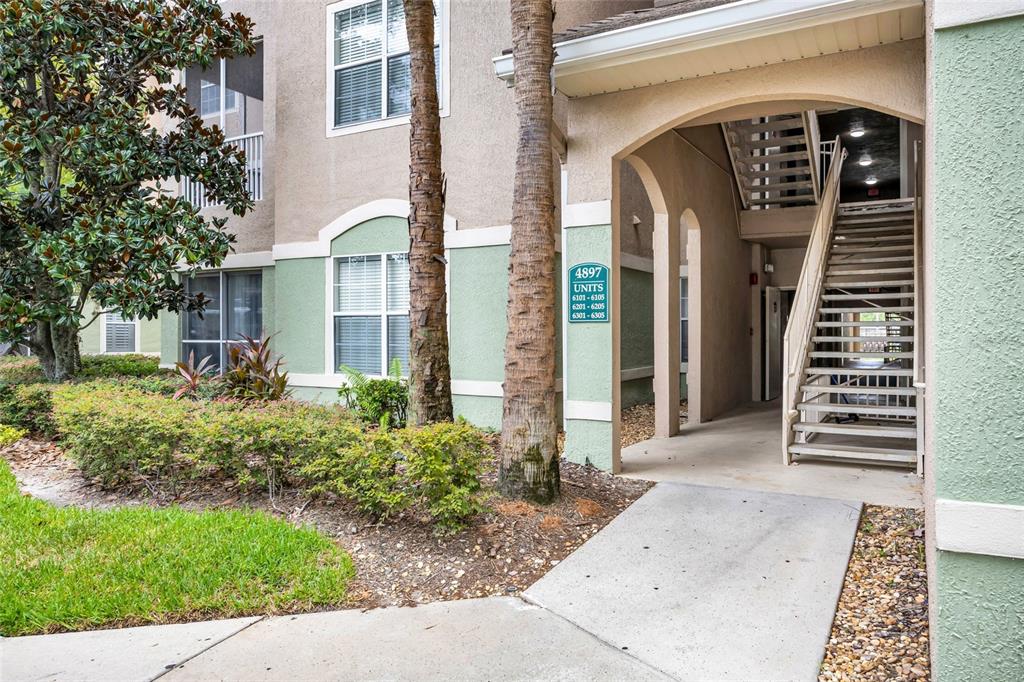An exterior view of an apartment building entrance with a staircase and unit number sign — 4897 CYPRESS WOODS DRIVE UNIT 6303, ORLANDO, FL