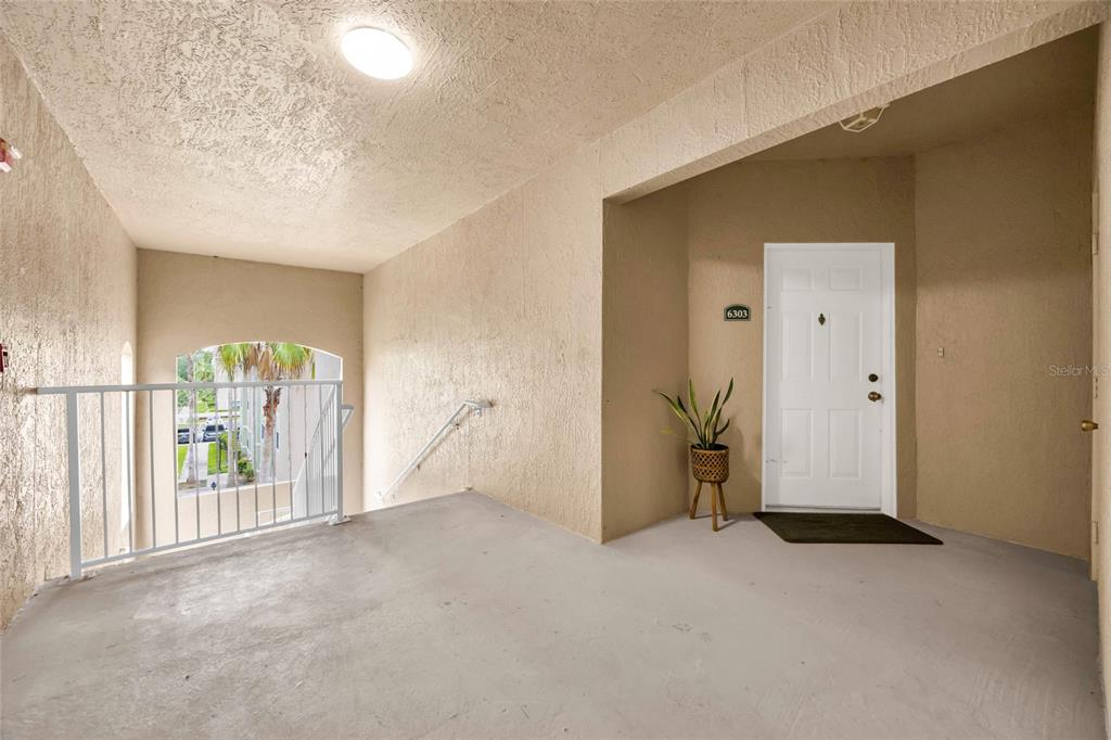 An exterior view of an apartment entryway with a white door, stairs, and a railing — 4897 CYPRESS WOODS DRIVE UNIT 6303, ORLANDO, FL