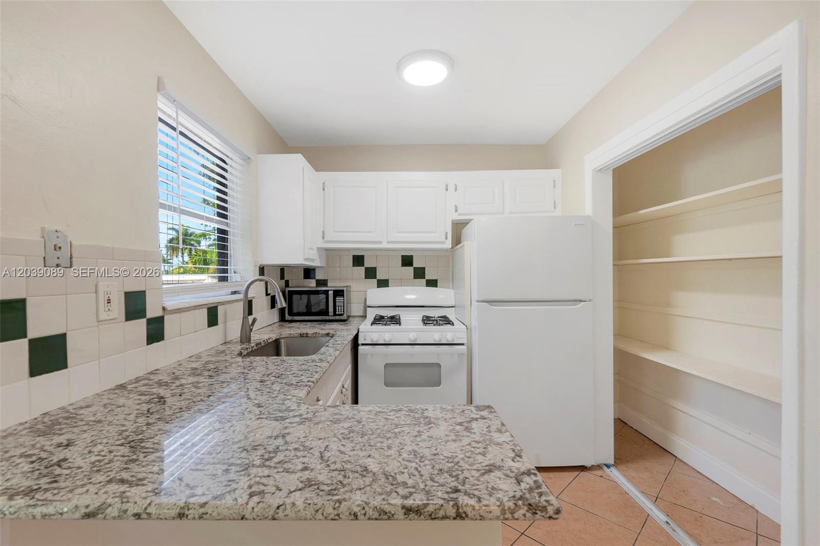 A kitchen features white cabinets, granite countertops, a gas stove, and an adjacent pantry closet — 2151 NW 64th Ave, Sunrise FL 33313, SUNRISE, FL